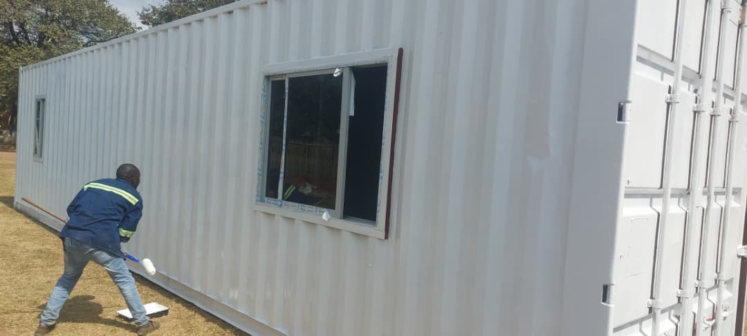 Team painting and finishing a converted container